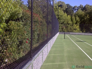 Chainwire tennis court fence installed on top of filled wall